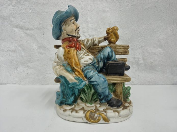 Vintage Ceramic Figurine of a Man Seated on a Bench with a Squirrel