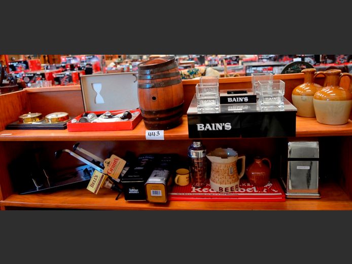 LOT ON 2 SHELVES BAR PARAPHERNALIA: SMALL CERAMIC FLAGONS, METAL BOUND KEG, OPTICS, WHISKY DISPLAY WITH GLASSES, ICE CRUSHER, etc