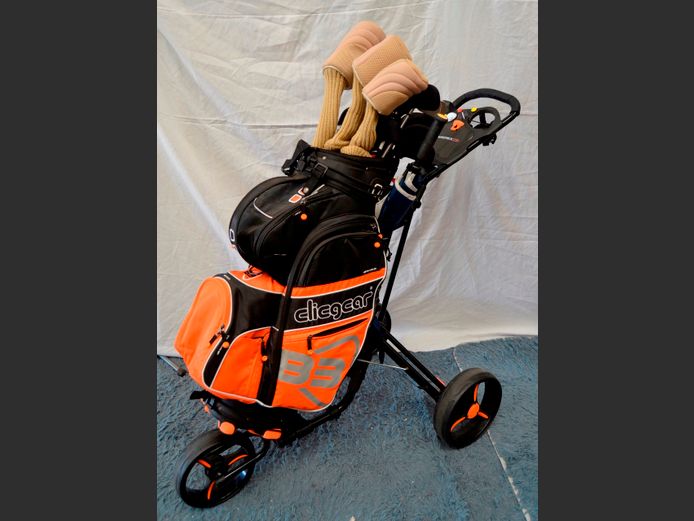 ORANGE CLICGEAR GOLF BAG WITH CLUBS ON TROLLEY