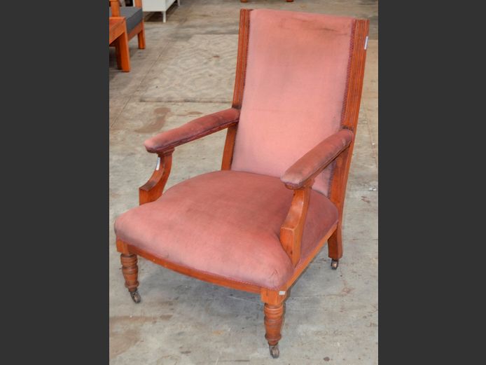 PINK UPHOLSTERED LOW ARMCHAIR ON CASTORS [Needs a clean]